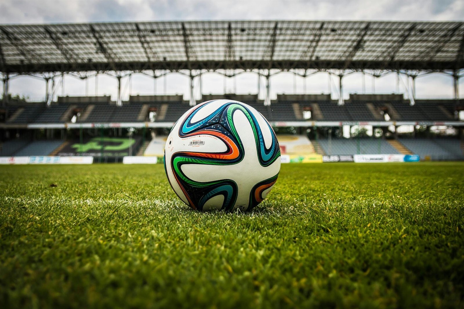 Le Programme Sportif A vibrant soccer ball rests on a lush green field inside an empty stadium, capturing the essence of sports.